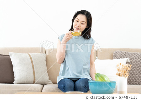 Middle woman drinking herbal tea on sofa Middle woman drinking herbal tea on sofa 67487113