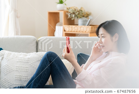 看著智能手機在客廳裡的中年女人 看著智能手機在客廳裡的中年女人 67487656