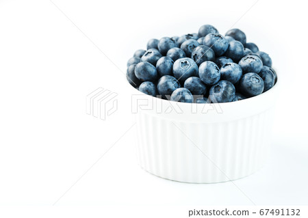 Blueberries in a white Cup on a white background. 67491132