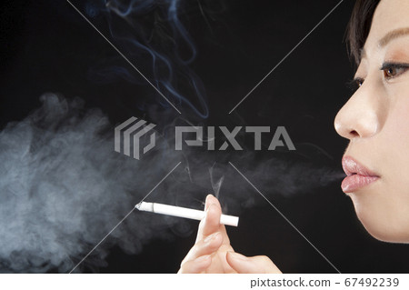 A woman smoking a cigarette 67492239