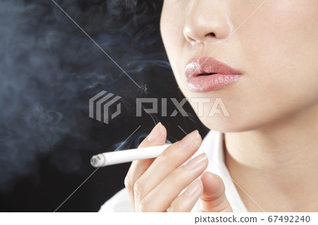 A woman smoking a cigarette 67492240