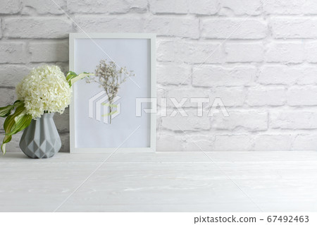 Green hydrangea in a gray vase in the Nordic style stands on a white wooden table. Background old brick. Bundle, copy space. Green hydrangea in a gray vase in the Nordic style stands on a white wooden table. Background old brick. Bundle, copy space. 67492463