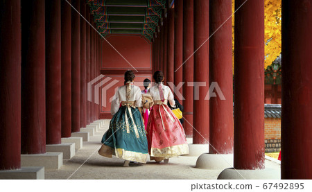 Asian girl in hanbok dress walk in autumn leaves 67492895
