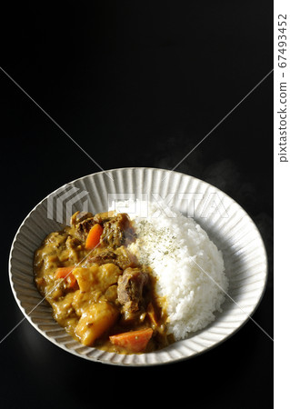 Curry and rice containing a lot of steamed potatoes, carrots and beef tendon (black background) 67493452