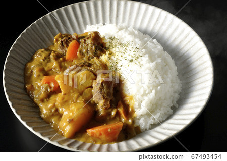 Curry and rice containing a lot of steamed potatoes, carrots and beef tendon (black background) Curry and rice containing a lot of steamed potatoes, carrots and beef tendon (black background) 67493454