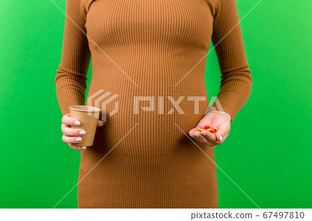 Close up of a paper cup and a heap of pills in 67497810