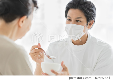 Nursing staff wearing masks to help with meals 67497861