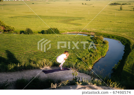 Young relaxed woman practicing yoga, standing in Eagle exercise, Garudasana pose. 67498574