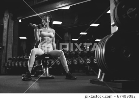 Fitnesswoman training with dumbbells, monochrome. 67499082