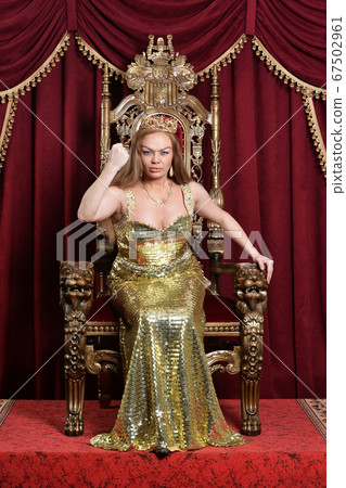 Portrait of young woman in crown sitting in chair Portrait of young woman in crown sitting in chair 67502961