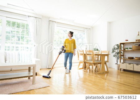 Young woman cleaning the living room 67503612