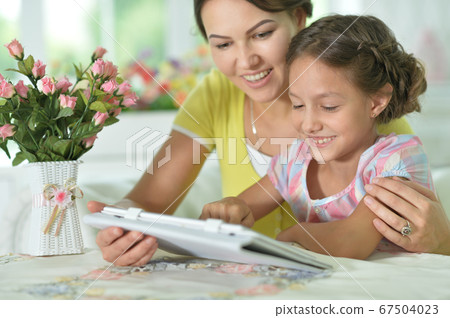 Happy mother and daughter using tablet together at home Happy mother and daughter using tablet together at home 67504023
