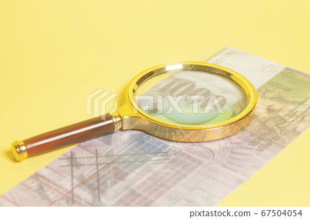 Swiss 1000 Franc banknotes under magnifying glass 67504054