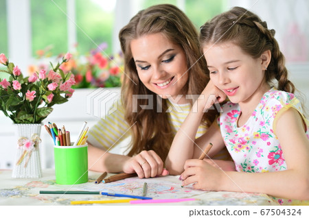 Portrait of girl with mother drawing at home 67504324