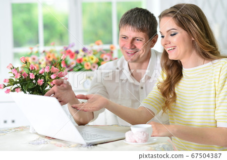 Young couple sitting at table and using laptop 67504387