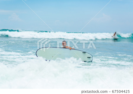 The guy is swimming on the surf board on the 67504425