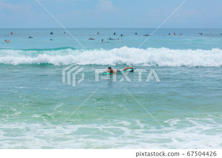 The guy is swimming on the surf board on the 67504426