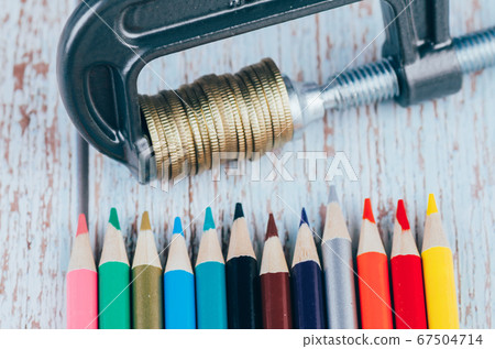 stacking coin squeezing in a G-clamp, and colorful marker pen on wooden desk. stacking coin squeezing in a G-clamp, and colorful marker pen on wooden desk. 67504714