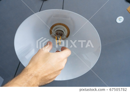 Close-up. A hand changes a light bulb in a stylish 67505782