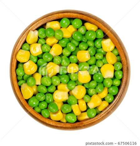 Green peas and corn in wooden bowl. Mixed vegetables. Seeds of pod fruit Pisum sativum and blanched yellow vegetable maize, Zea mays, also called sugar or pole corn. Closeup, from above, food photo. 67506116