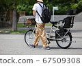 A mother pushing a bicycle for children 67509308