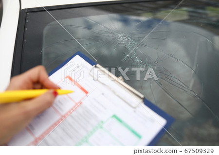 An agent draws up documents for broken windshield in car. 67509329