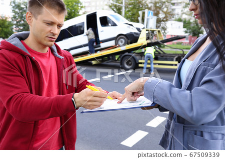 Man and woman fill out paperwork after car accident. 67509339