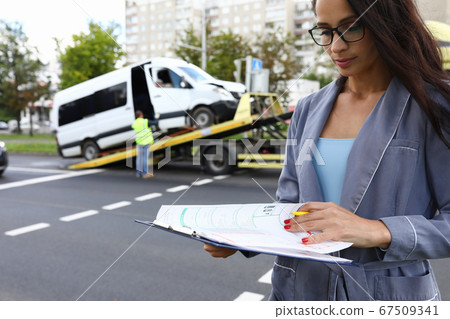 Female agent fills out insurance at the scene of accident. 67509341