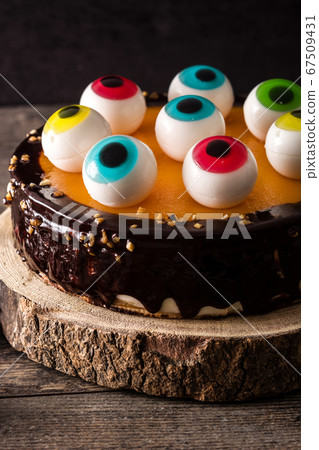 Halloween cake with candy eyes decoration on wooden table 67509431