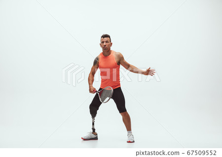 Athlete with disabilities or amputee isolated on white studio background. Professional male tennis player with leg prosthesis training and practicing in studio. 67509552