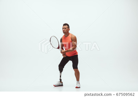 Athlete with disabilities or amputee isolated on white studio background. Professional male tennis player with leg prosthesis training and practicing in studio. 67509562