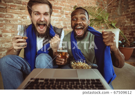 Excited football fans watching sport match at home, remote support of favourite team during coronavirus pandemic outbreak 67509612