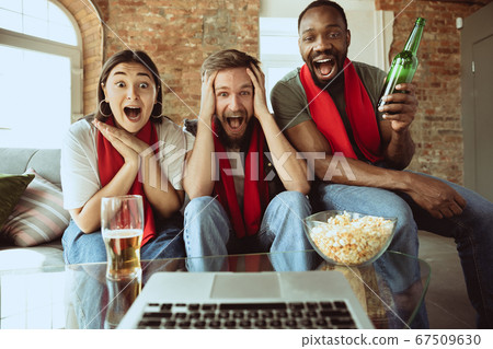 Excited football fans watching sport match at home, remote support of favourite team during coronavirus pandemic outbreak 67509630