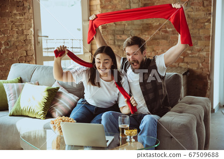 Excited football fans watching sport match at home, remote support of favourite team during coronavirus pandemic outbreak Excited football fans watching sport match at home, remote support of favourite team during coronavirus pandemic outbreak 67509688