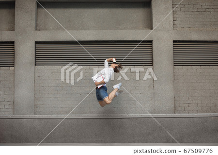 Jumping young man in front of buildings, on the run in jump high 67509776