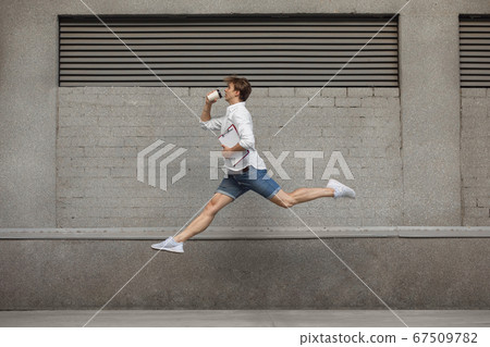 Jumping young man in front of buildings, on the run in jump high 67509782