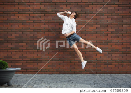 Jumping young man in front of buildings, on the run in jump high 67509809