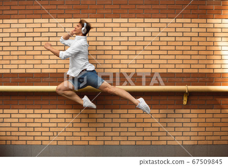 Jumping young man in front of buildings, on the run in jump high Jumping young man in front of buildings, on the run in jump high 67509845