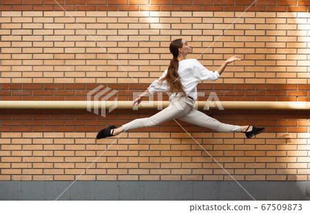 Jumping young woman in front of buildings, on the run in jump high Jumping young woman in front of buildings, on the run in jump high 67509873