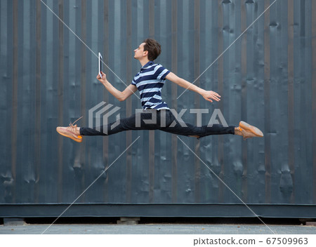 Jumping young buinessman in front of buildings, on the run in jump high 67509963