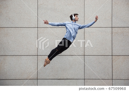 Jumping young buinessman in front of buildings, on the run in jump high 67509968