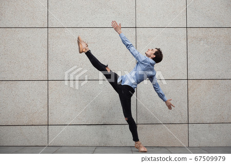 Jumping young buinessman in front of buildings, on the run in jump high 67509979