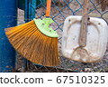 Old broom and dirty scoop near the iron blue mesh fence 67510325