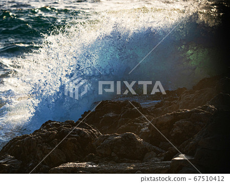 Strong wave splashing against a rock in the sea Strong wave splashing against a rock in the sea 67510412
