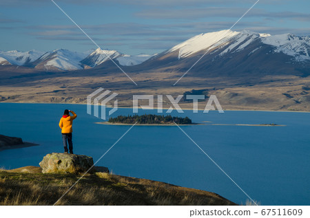 Girl in yellow jacket looking at Lake Tekapo from Mount John observatory, South Island, New Zealand 67511609