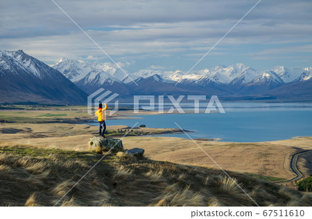 Girl in yellow jacket looking at Lake Tekapo from Mount John observatory, South Island, New Zealand 67511610