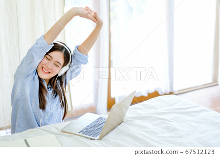 Beautiful woman do stretching in front laptop in bedroom with morning light 67512123