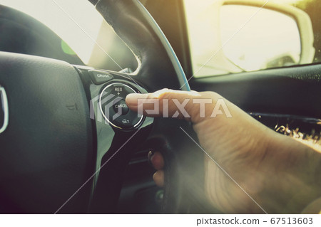 Driver hand pressing to adaptive cruise control button Driver hand pressing to adaptive cruise control button 67513603