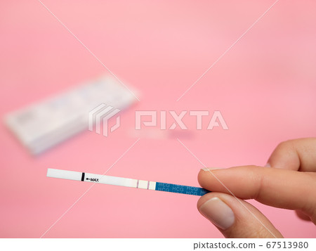 Female hand holding positive pregnancy test isolated on pink background. The abbreviation HCG on the blue bar means Human chorionic gonadotropin is a hormone produced by cells that are surrounding a Female hand holding positive pregnancy test isolated on pink background. The abbreviation HCG on the blue bar means Human chorionic gonadotropin is a hormone produced by cells that are surrounding a 67513980