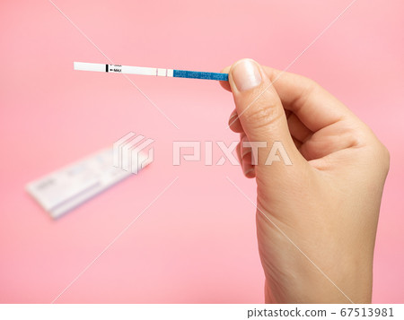 Female hand holding positive pregnancy test isolated on pink background. The abbreviation HCG on the blue bar means Human chorionic gonadotropin is a hormone produced by cells that are surrounding a Female hand holding positive pregnancy test isolated on pink background. The abbreviation HCG on the blue bar means Human chorionic gonadotropin is a hormone produced by cells that are surrounding a 67513981